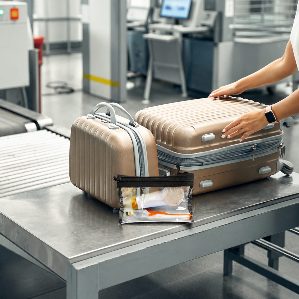 Detachable clear TSA pouch beside luggage on an airport security belt